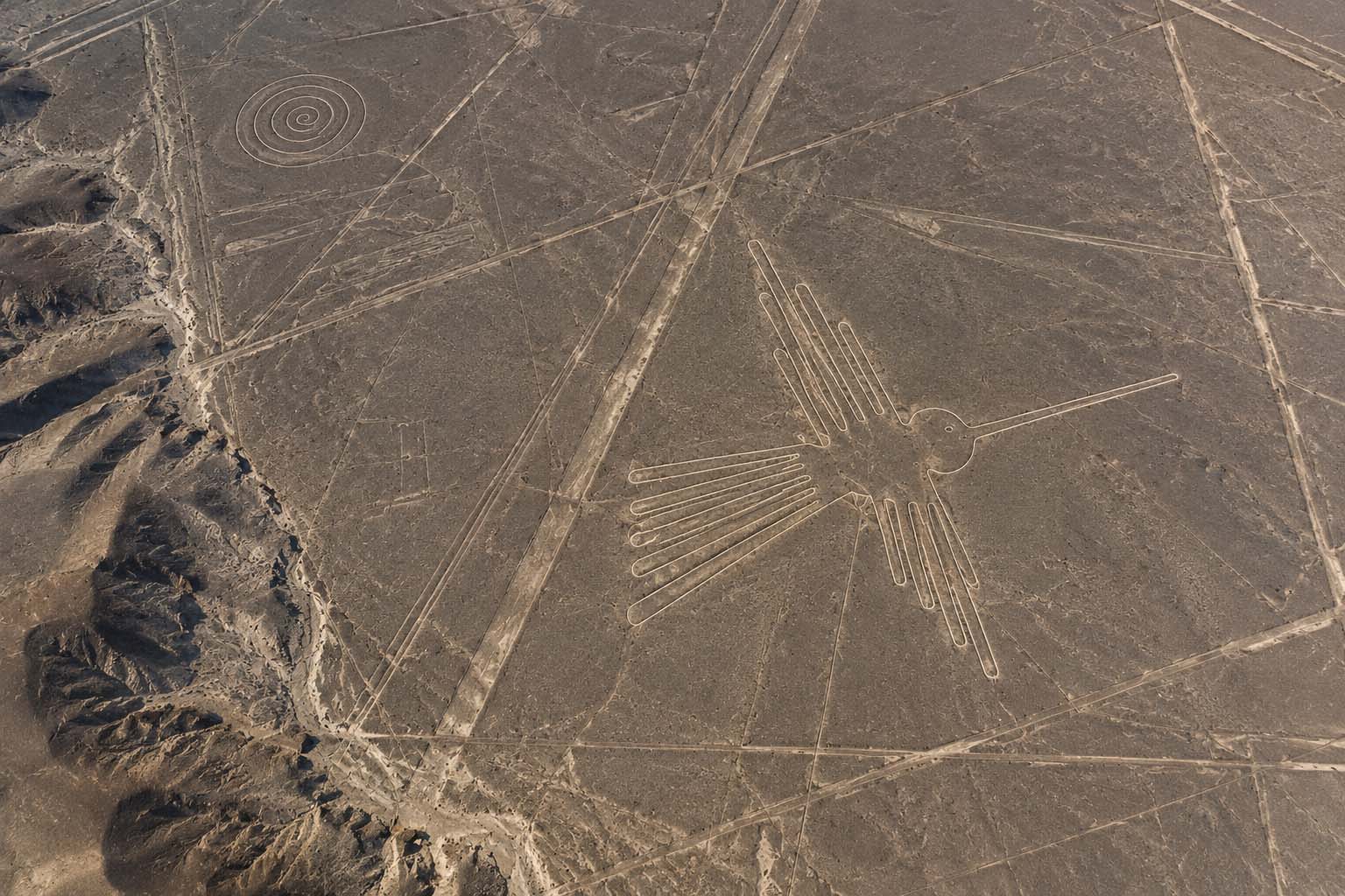 Aerial reconstruction of the Nazca desert landscape showing a hummingbird geoglyph, a spiral form, and intersecting geometric lines.